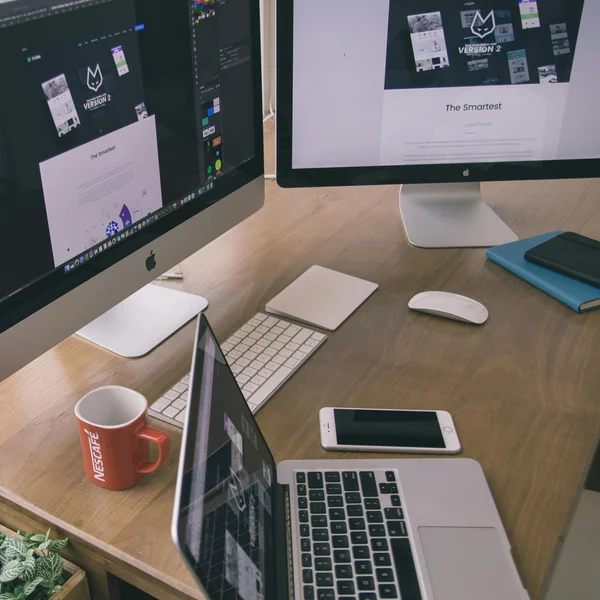 An iPhone and iMac and 2 large screens on a desk